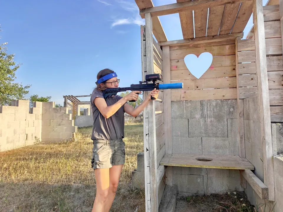Lasertag beim Partner Fun-Paintball: Spieler zielt neben einer Holztür mit herzförmigem Ausschnitt.