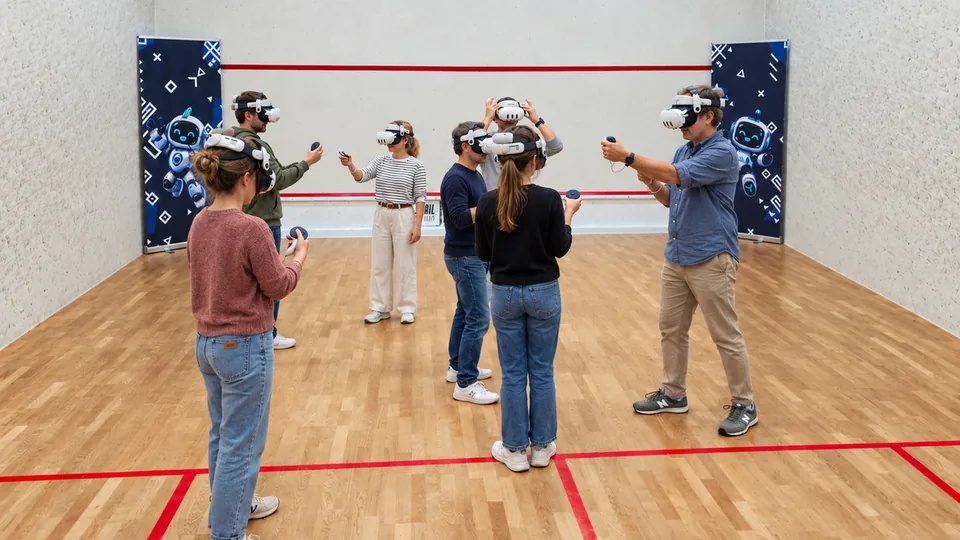 Sieben Erwachsene erleben gemeinsam VR mit Headsets und Controllern in einem Squashcourt.